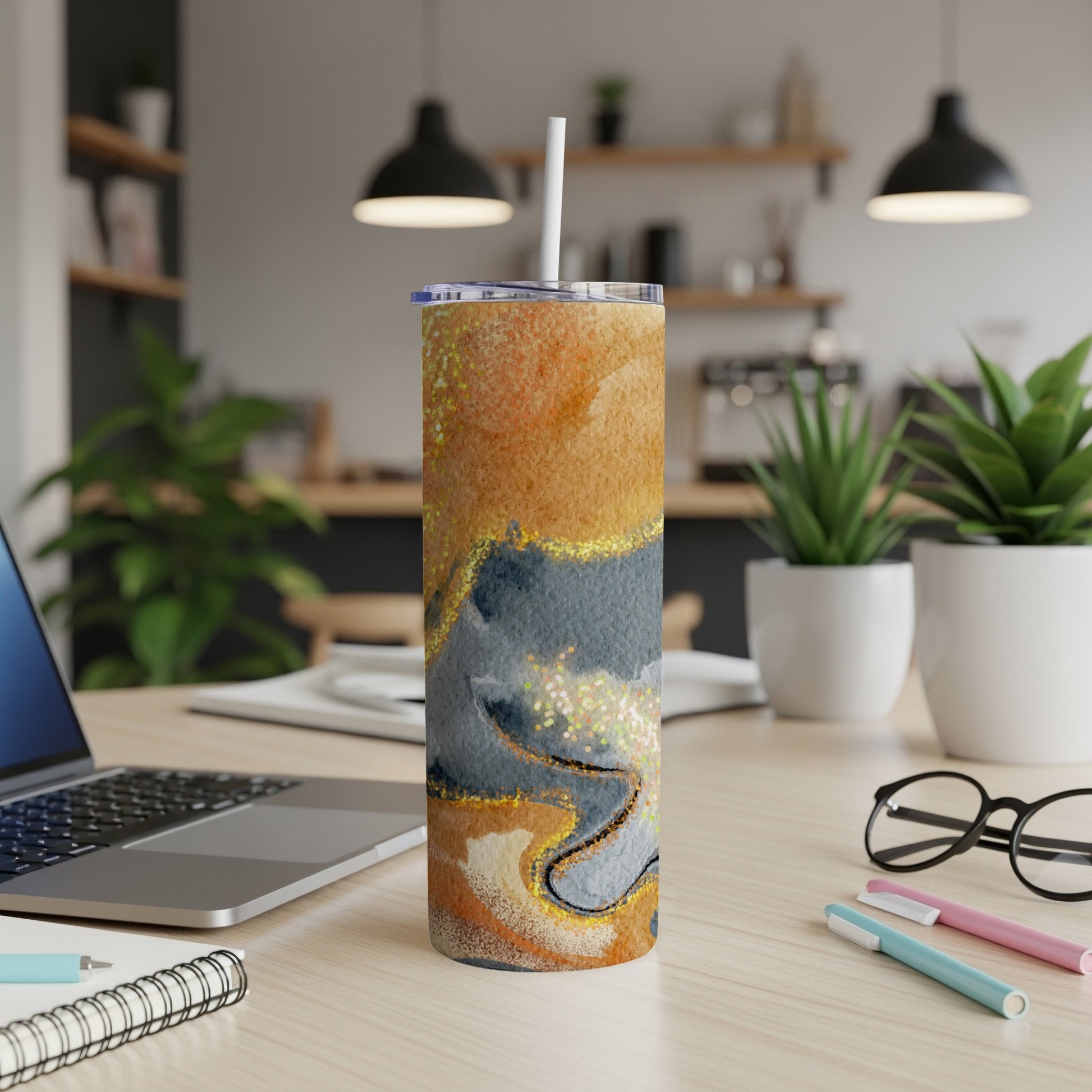 Abstract tumbler with marble-like design and straw on a desk.