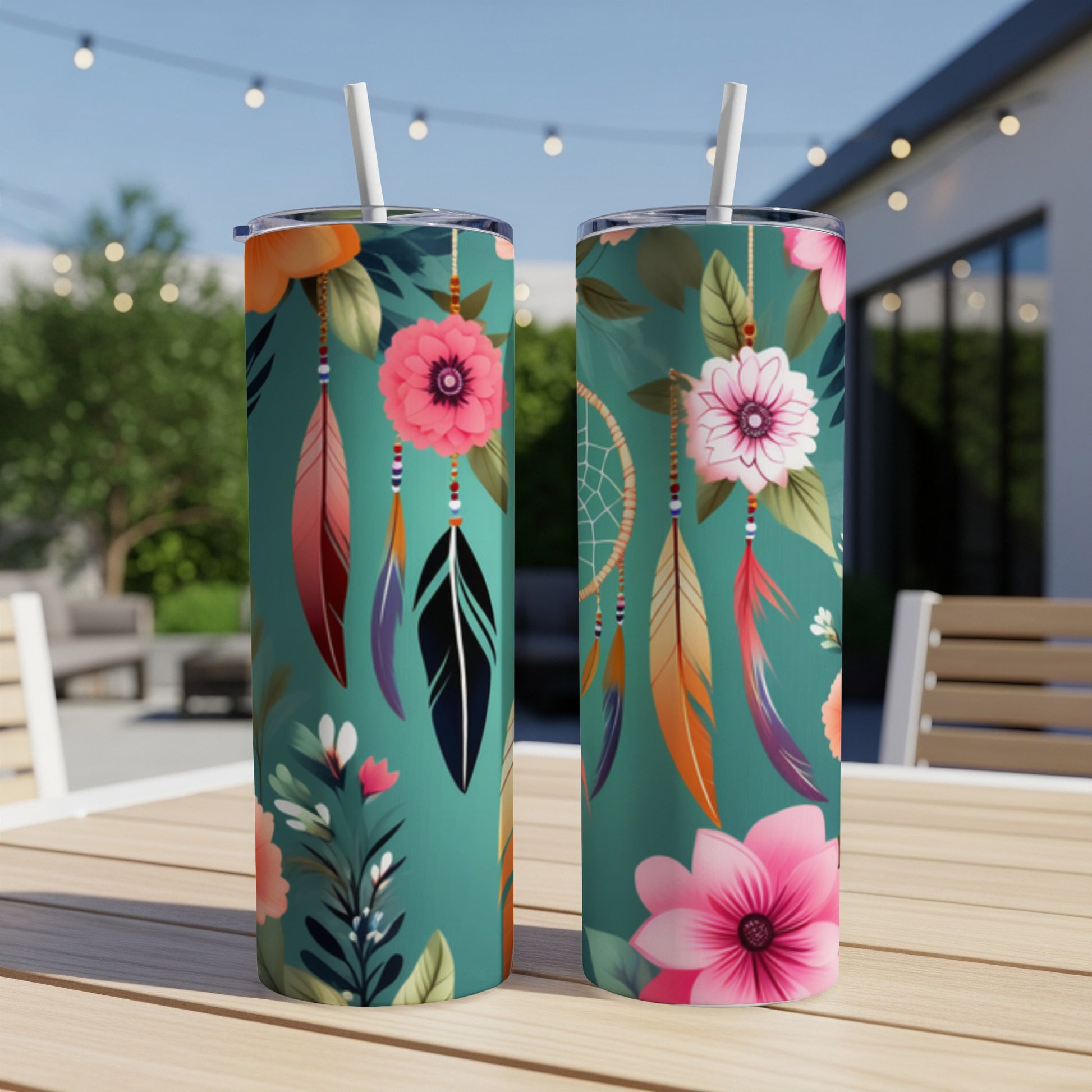 Two teal tumblers with floral and feather dreamcatcher designs, set on a table.