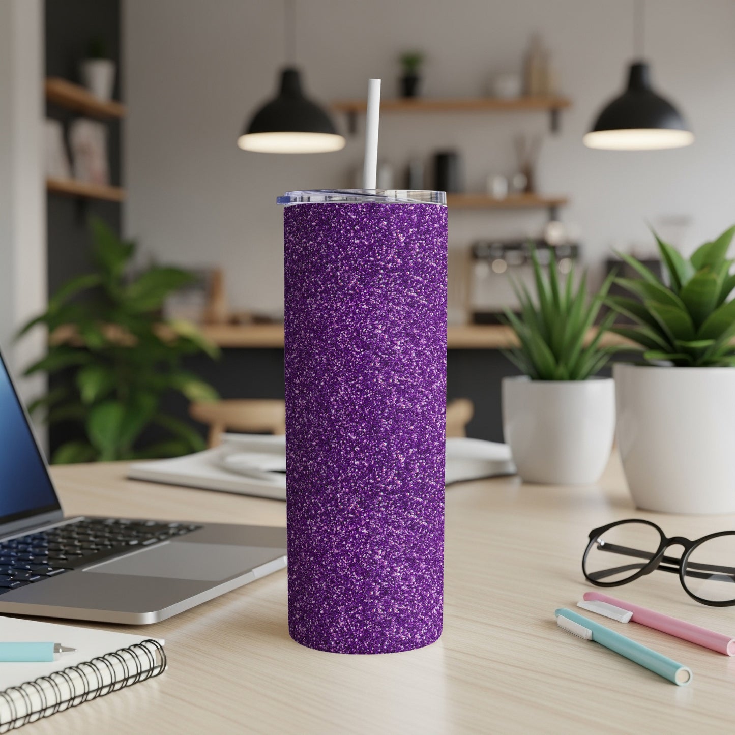 Purple glitter tumbler with straw on a desk next to a laptop and glasses.