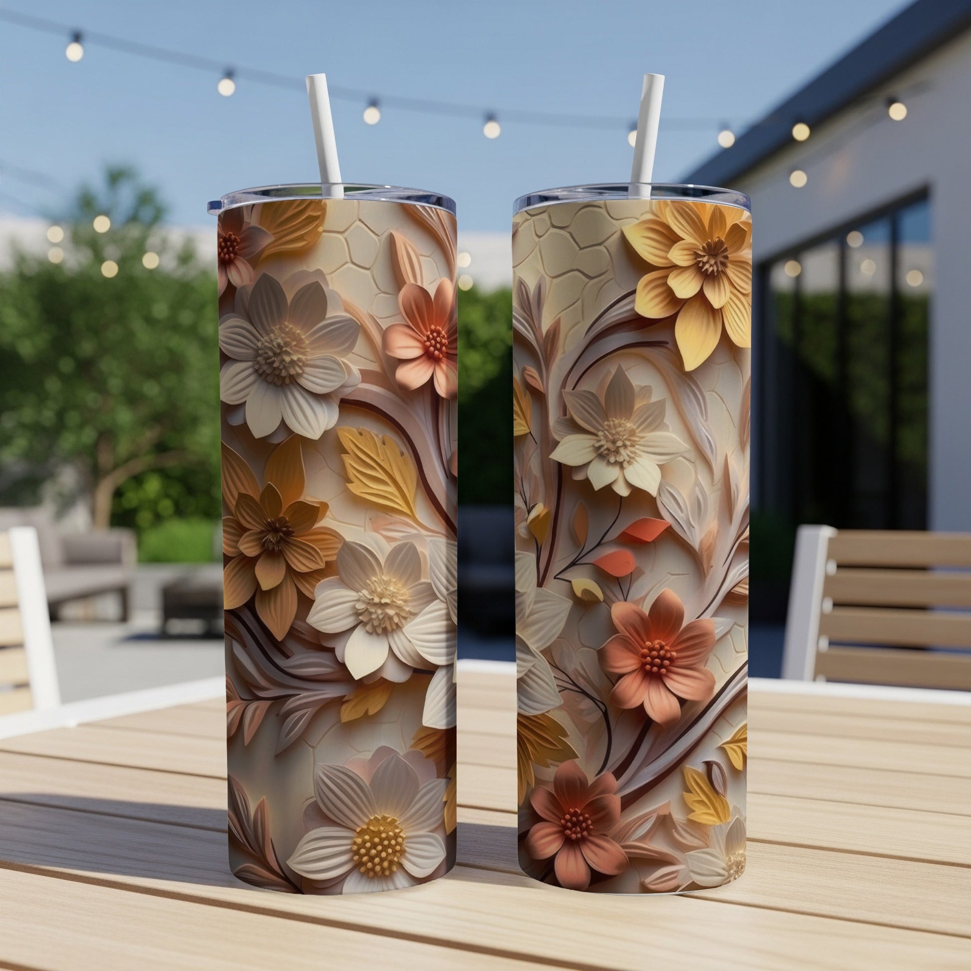 Two floral pattern tumblers with straws on a wooden table.