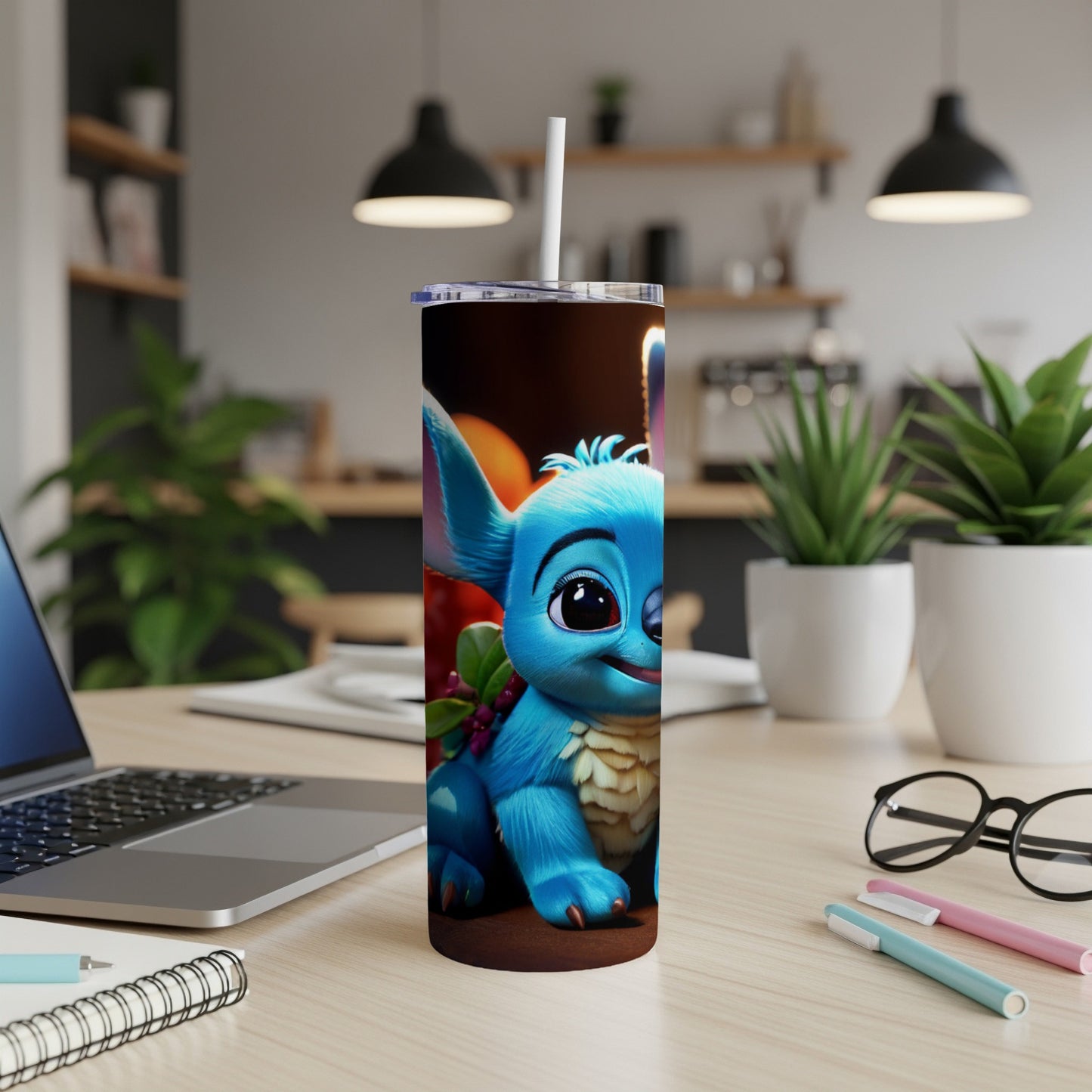 Blue cartoon alien character with big eyes sits on a desk with a laptop.
