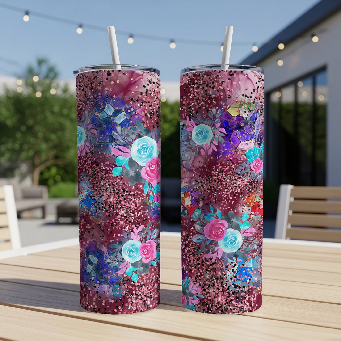 Two floral tumblers with glitter on a wooden table outdoors.