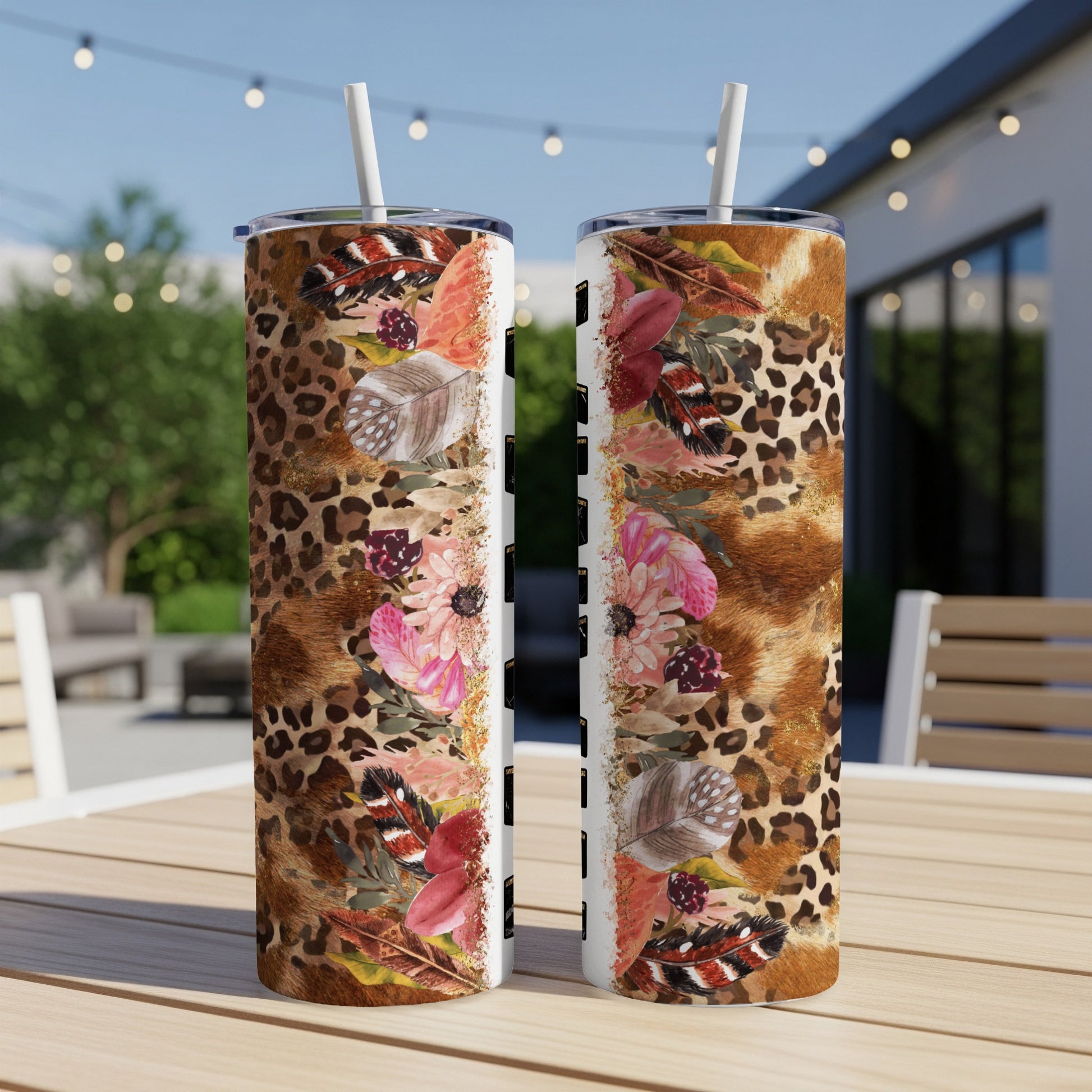 Two tumblers with leopard print, feathers, and floral designs on a wooden table.