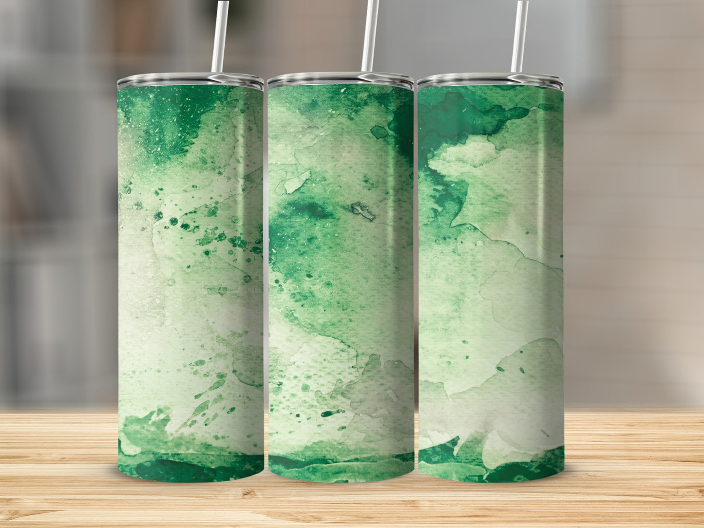 Three green watercolor tumblers with straws on a wooden surface.