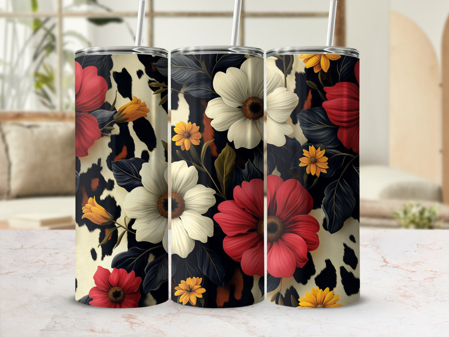 Three tumblers with floral and cow print designs on a table.