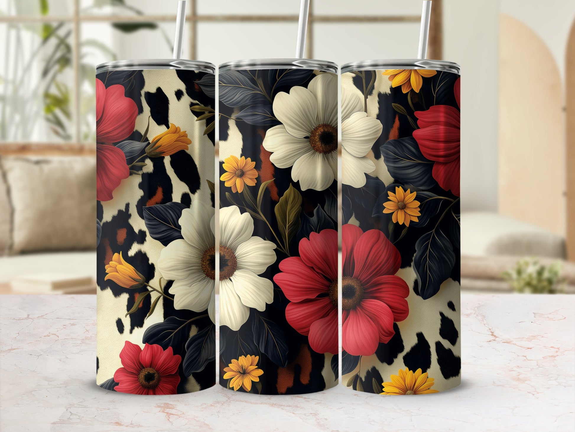 Three tumblers with floral and cow print designs on a table.