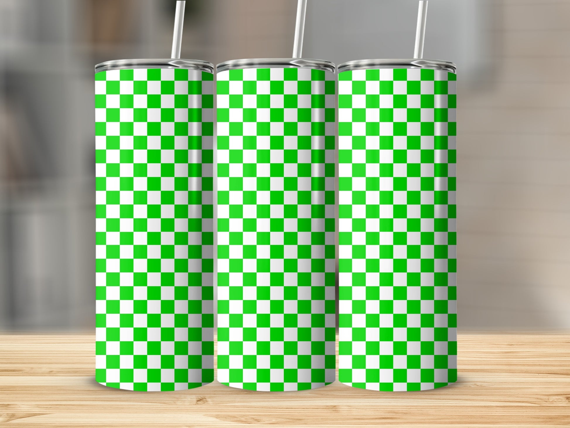 Three green and white checkered tumblers with straws on a wooden surface.