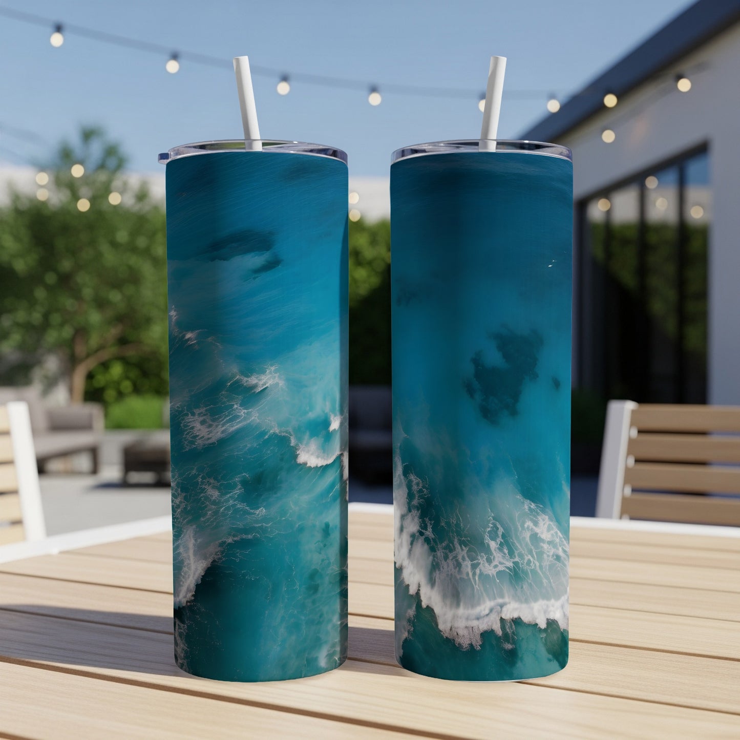 Two tumblers with ocean wave artwork on a table outdoors.