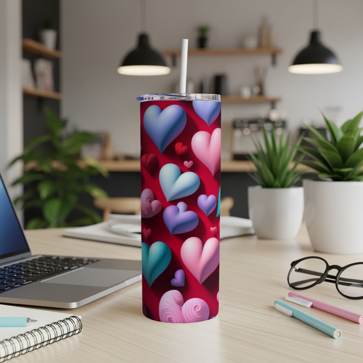 Red tumbler with scattered pink, purple, and blue hearts, on a desk.
