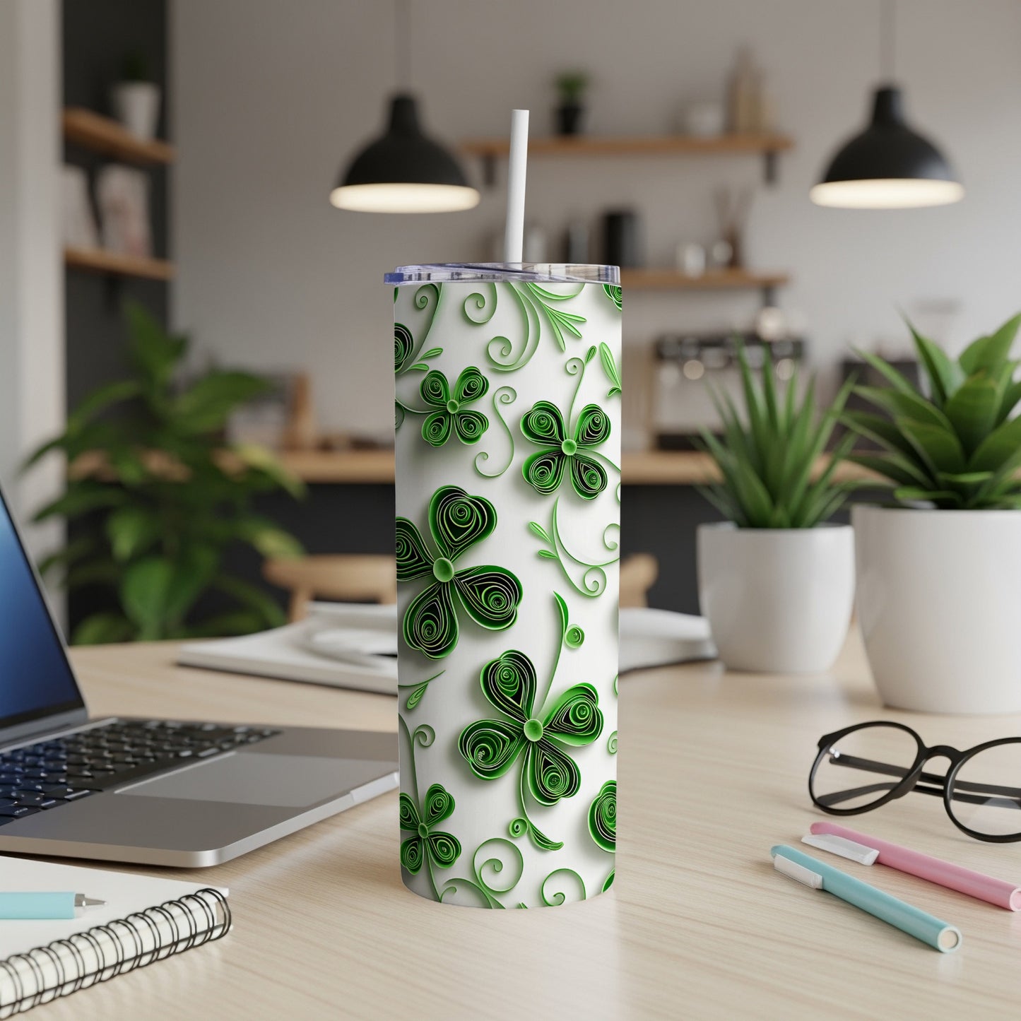 Green shamrock patterned tumbler with white lid and straw on desk.