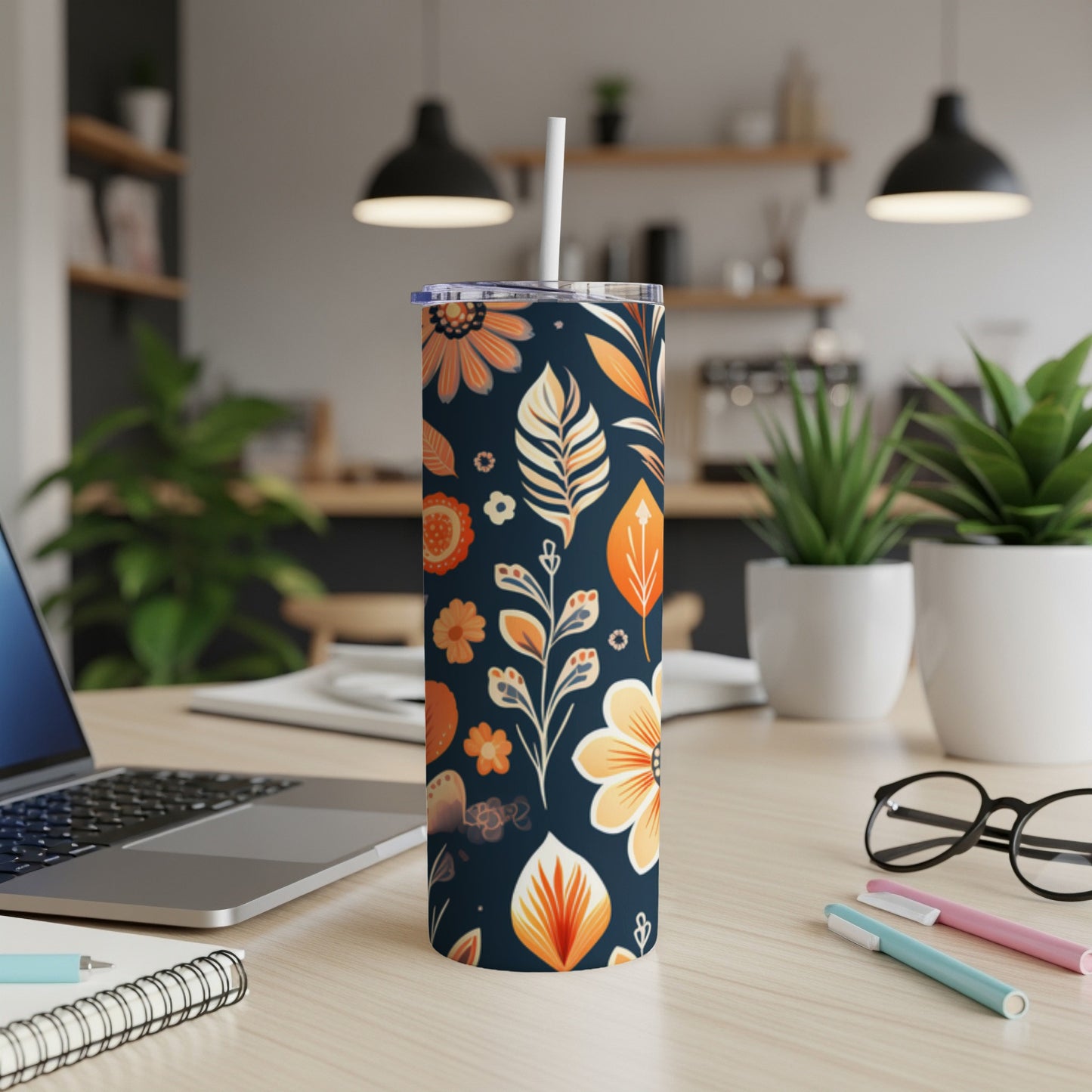 Dark tumbler with orange and white floral and leaf pattern, straw.