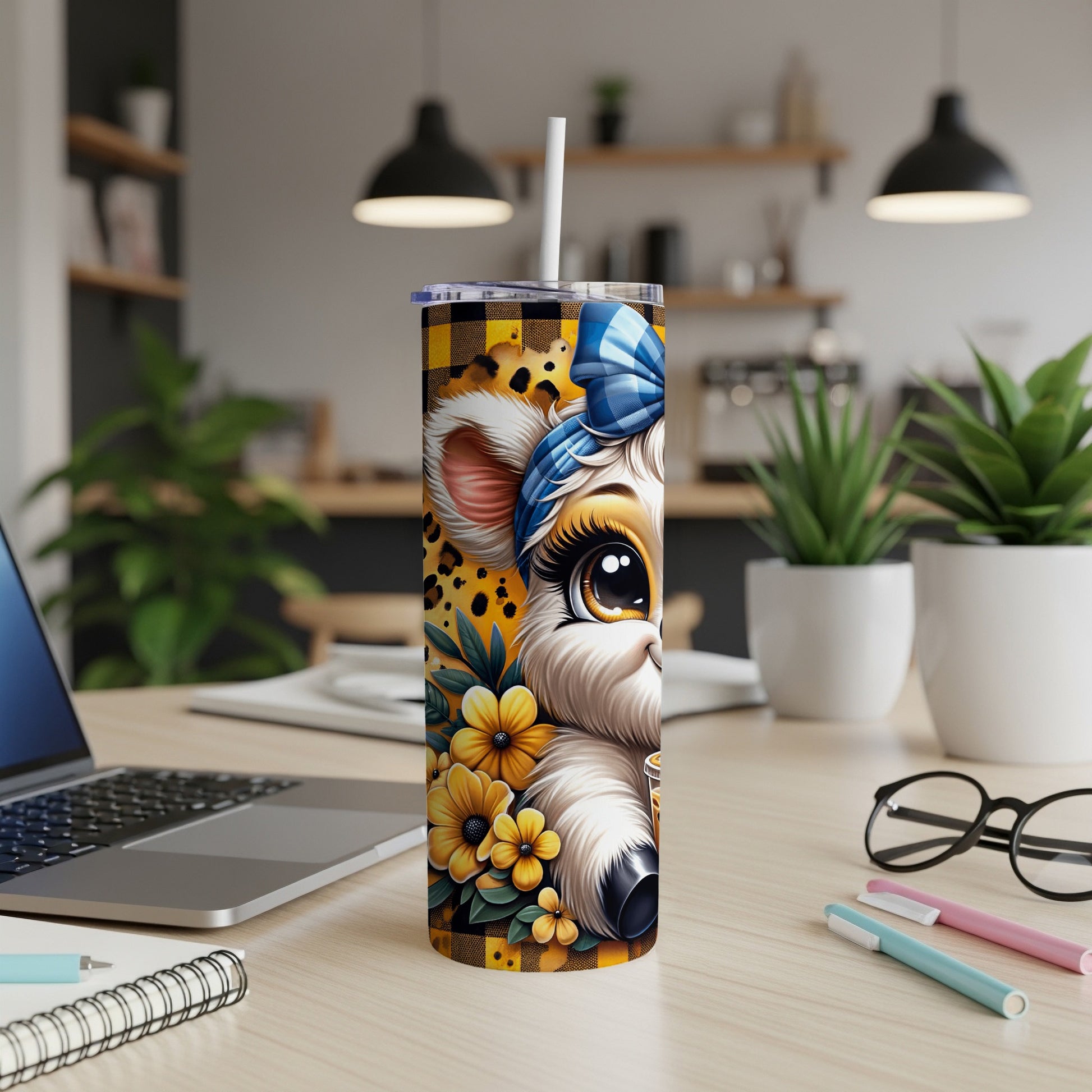 Cute cow tumbler with floral accents and straw on desk.