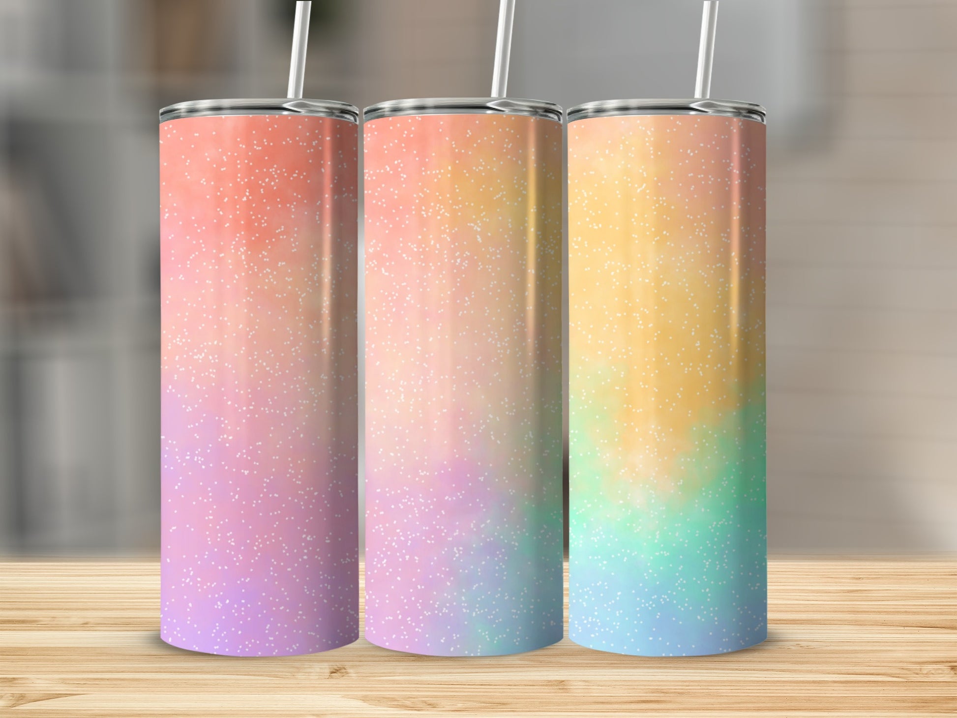Three tumblers with ombre gradient designs in pink, orange, yellow, green, and blue, with white speckles.