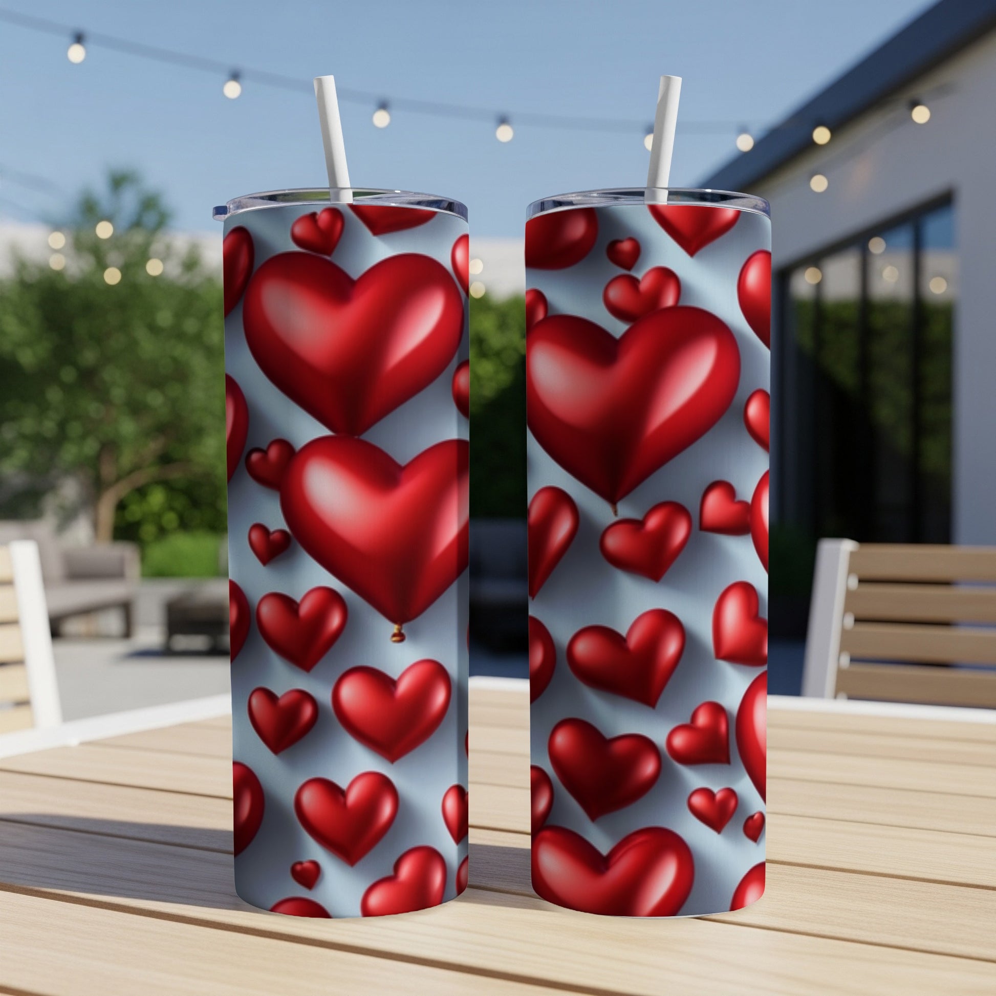 Two red heart-patterned tumblers with straws on a table.