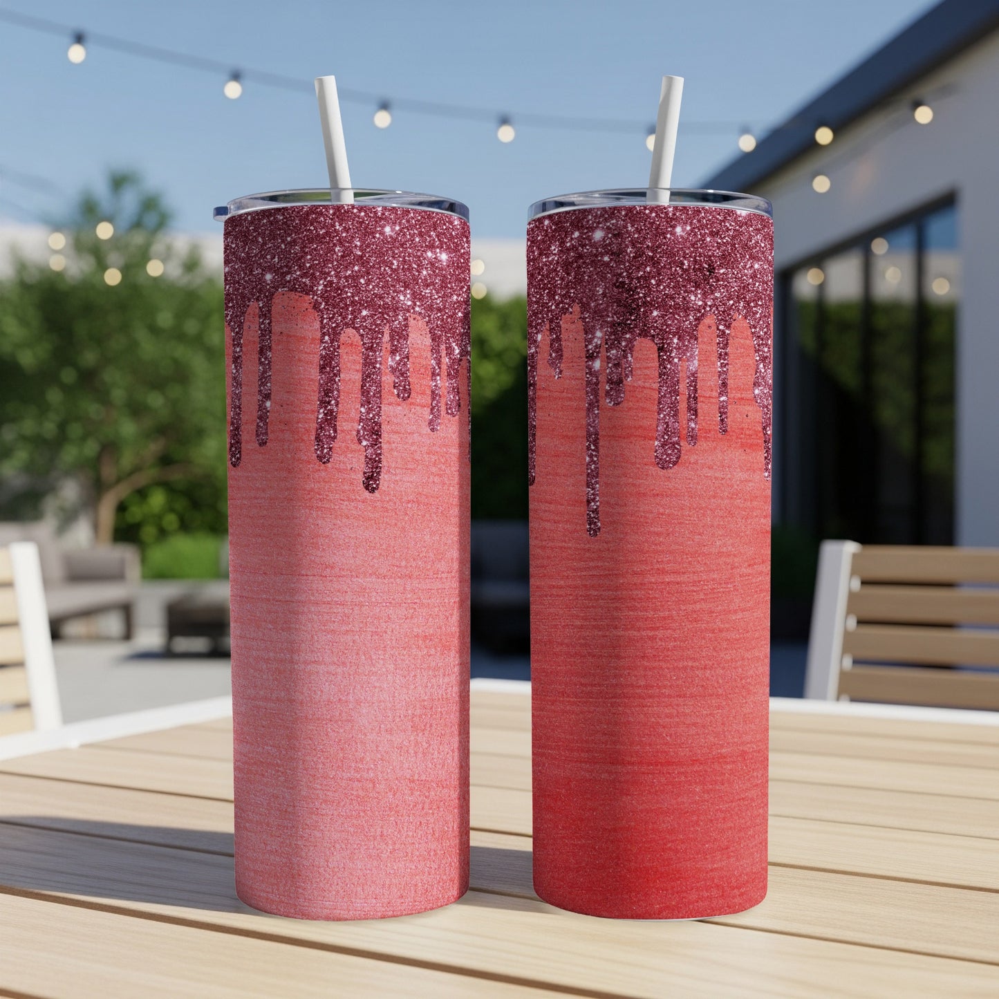 Two red glitter drip tumblers with white straws on a wooden table.