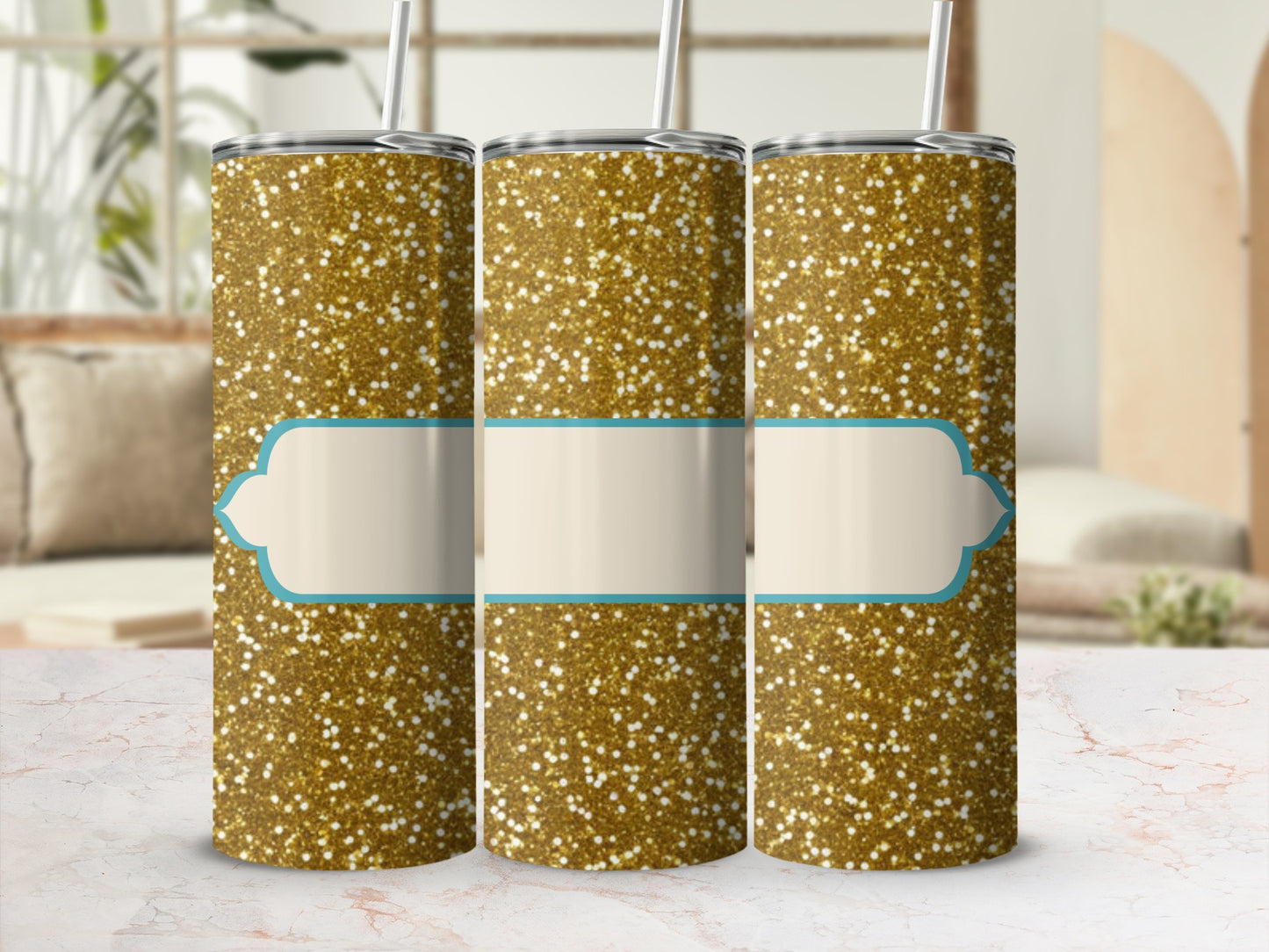 Three gold glitter tumblers with light blue labels in a studio setting.