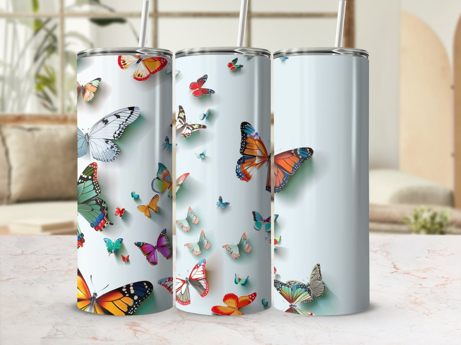Three tumblers with colorful butterfly designs on a light background.