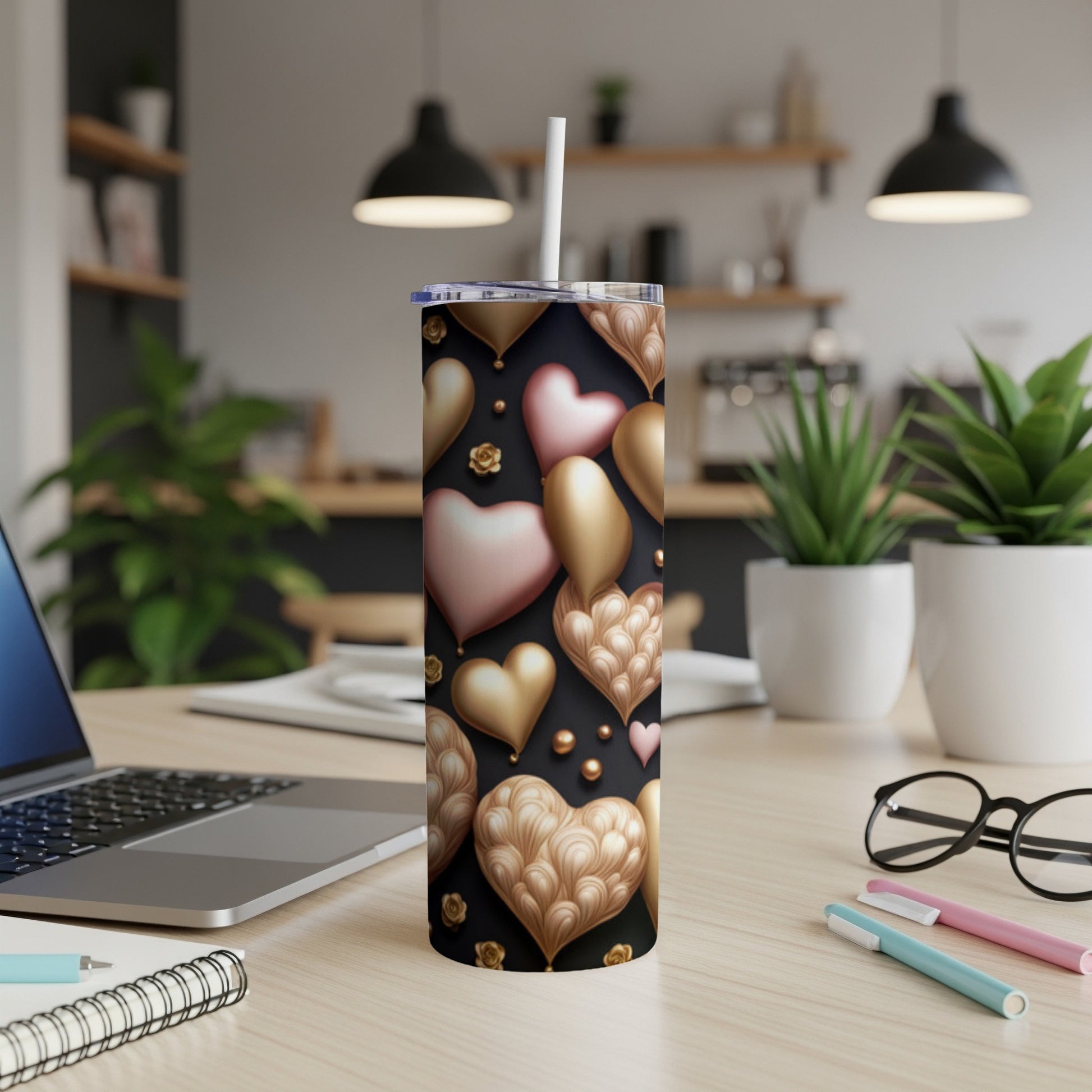 Gold and pink heart pattern tumbler with straw on a desk.