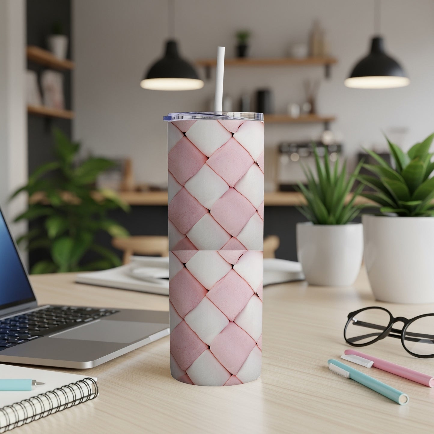Pink and white woven pattern tumbler with a straw, on a desk.