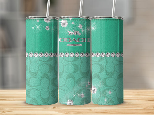 Three turquoise tumblers with diamonds and Coach logo on a wooden surface.