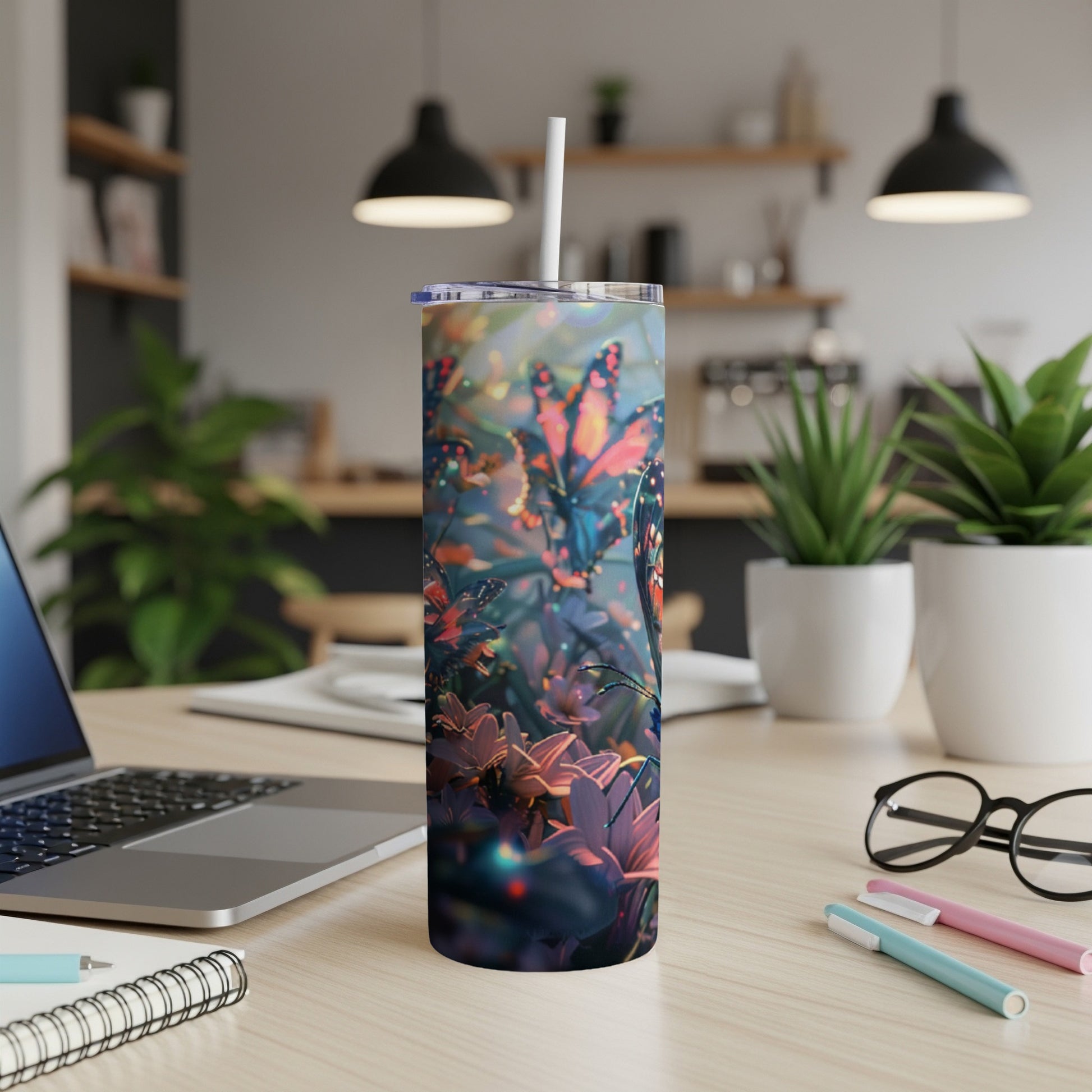 Butterfly tumbler with lid and straw on a desk with a laptop and pens.