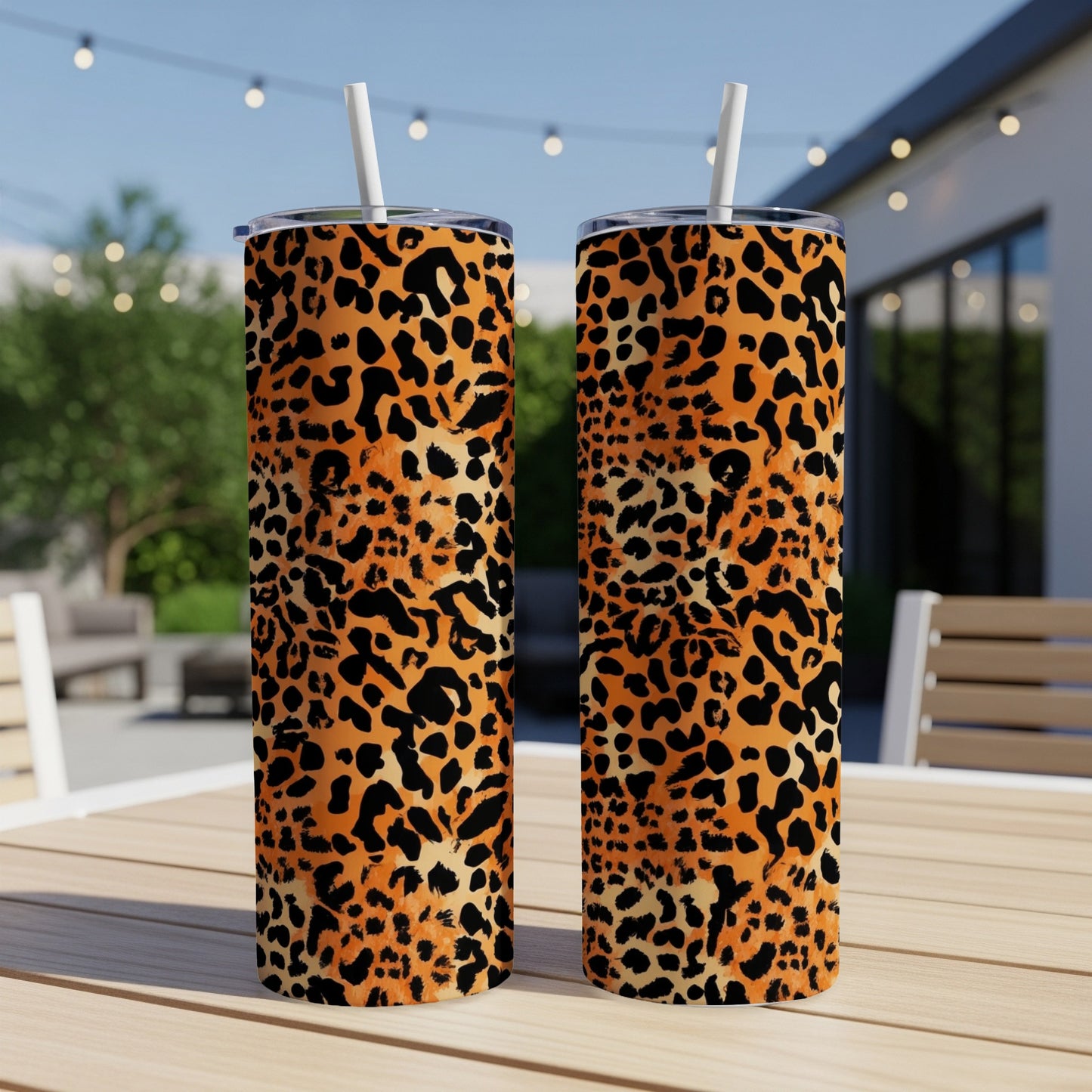 Two leopard print tumblers with straws on a wooden table.