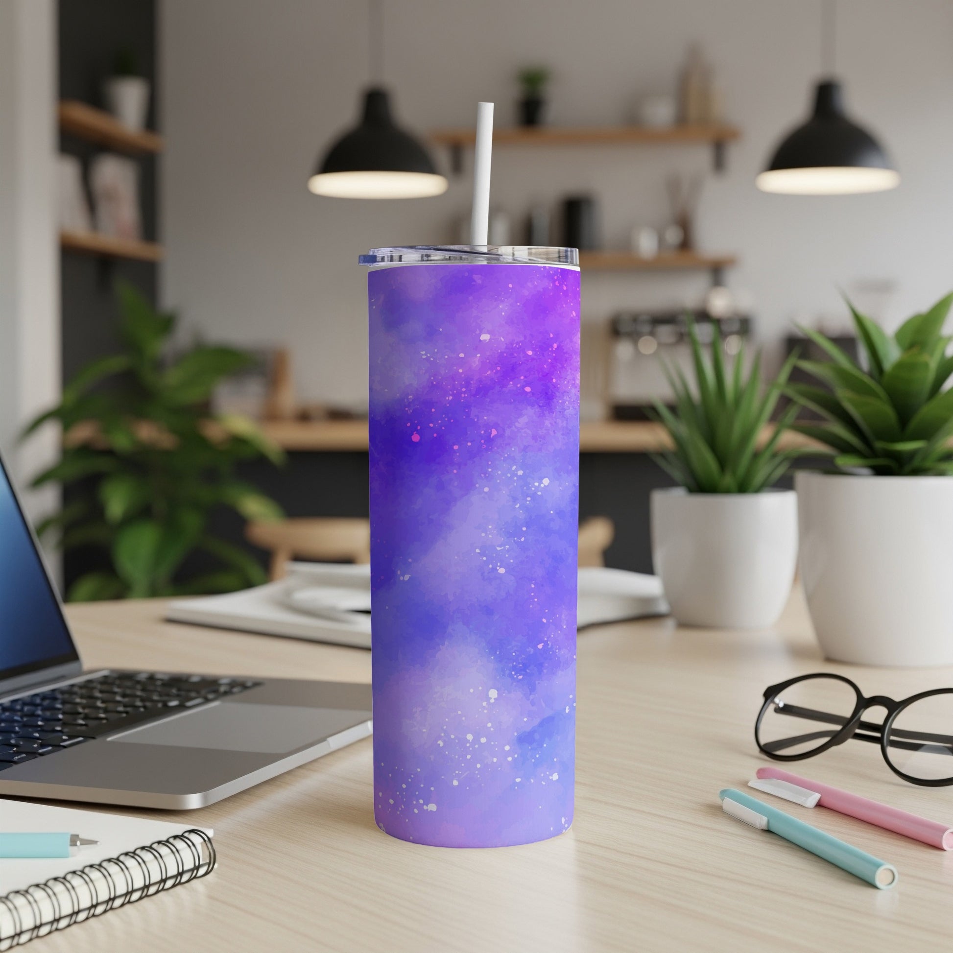Purple galaxy print tumbler with straw on a desk next to a laptop.
