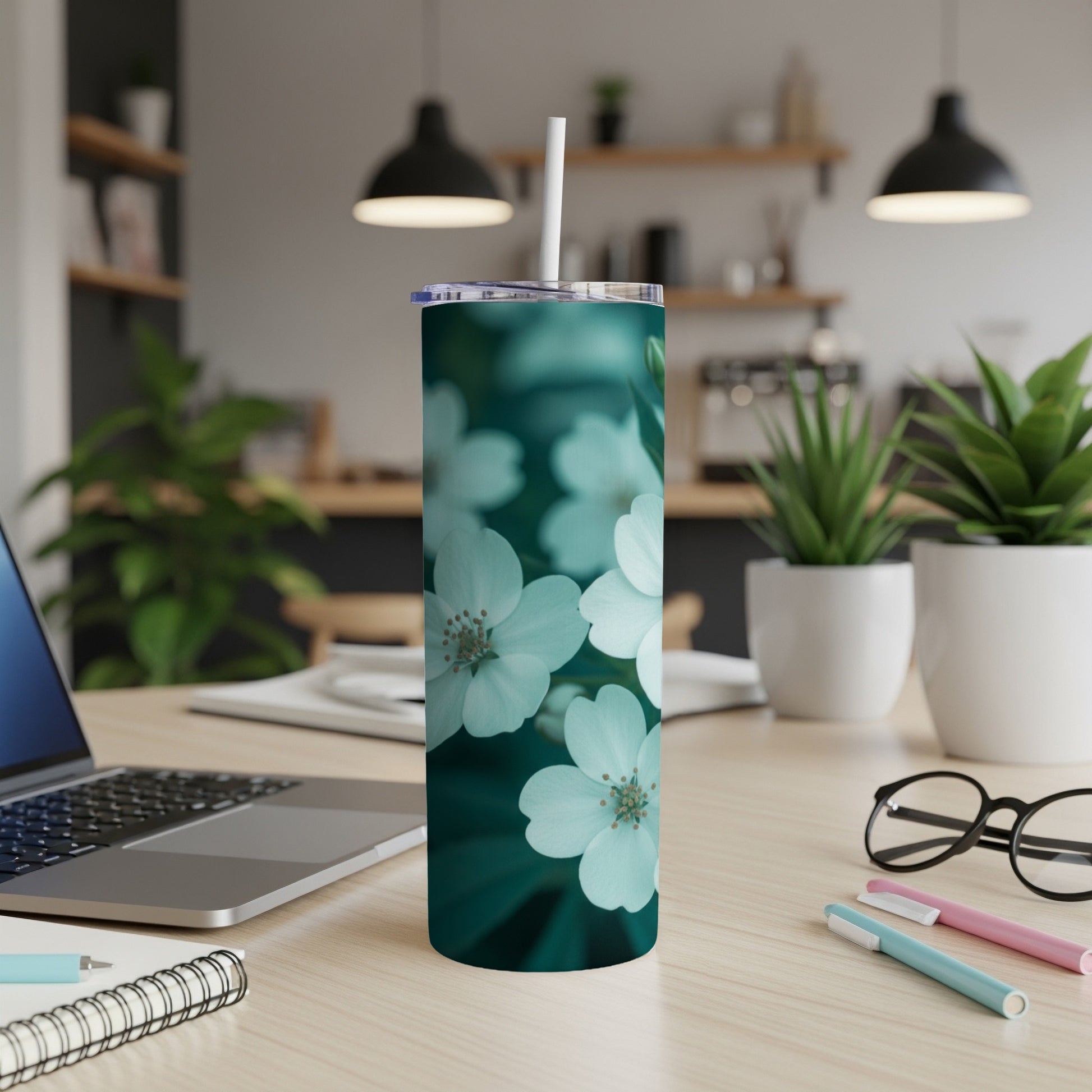 White cherry blossoms on a teal background on a tumbler with a straw.