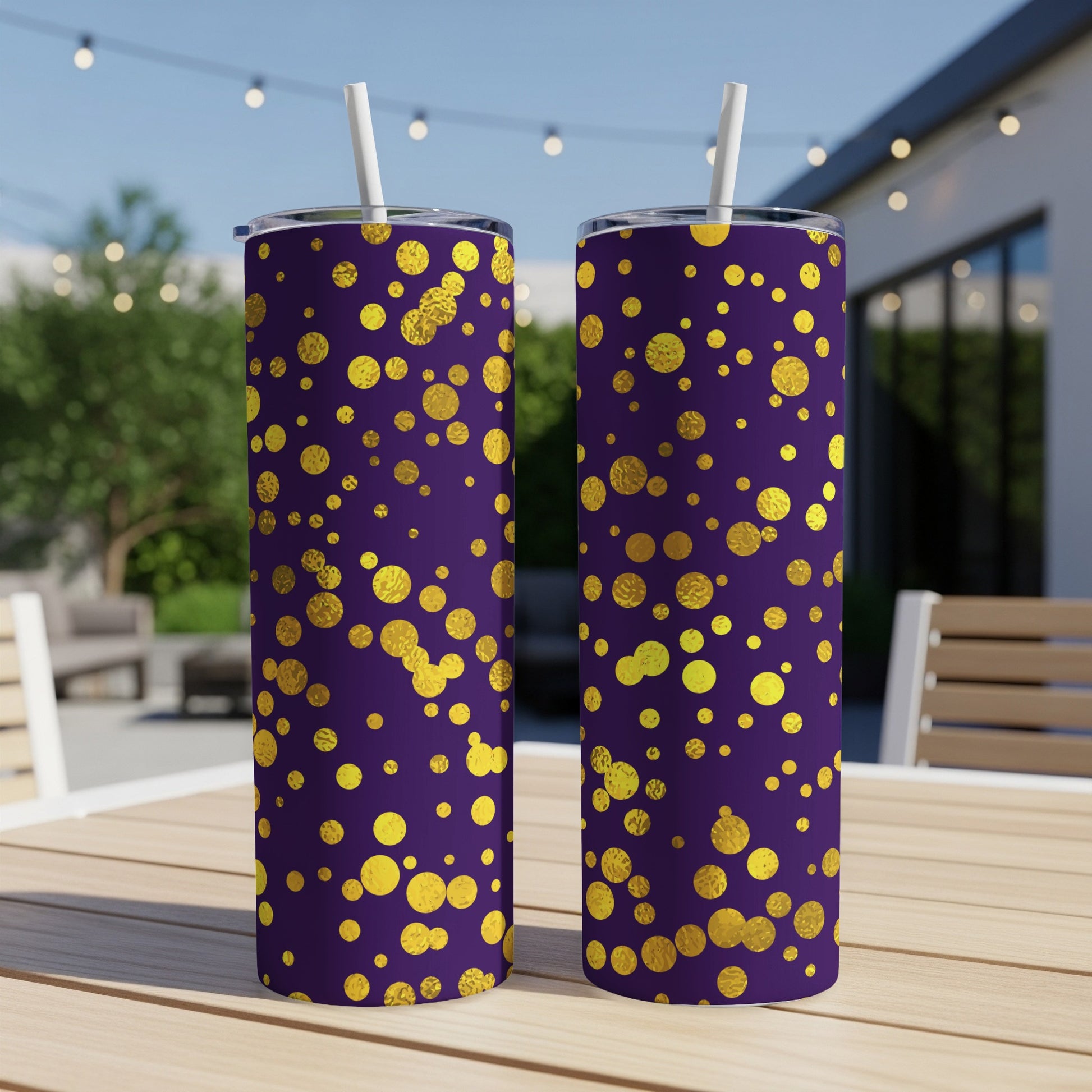 Two tumblers with gold circles on a purple background, each with a straw.