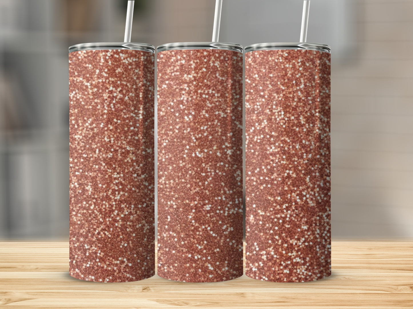 Three rose gold glitter tumblers with white straws on a wooden surface.