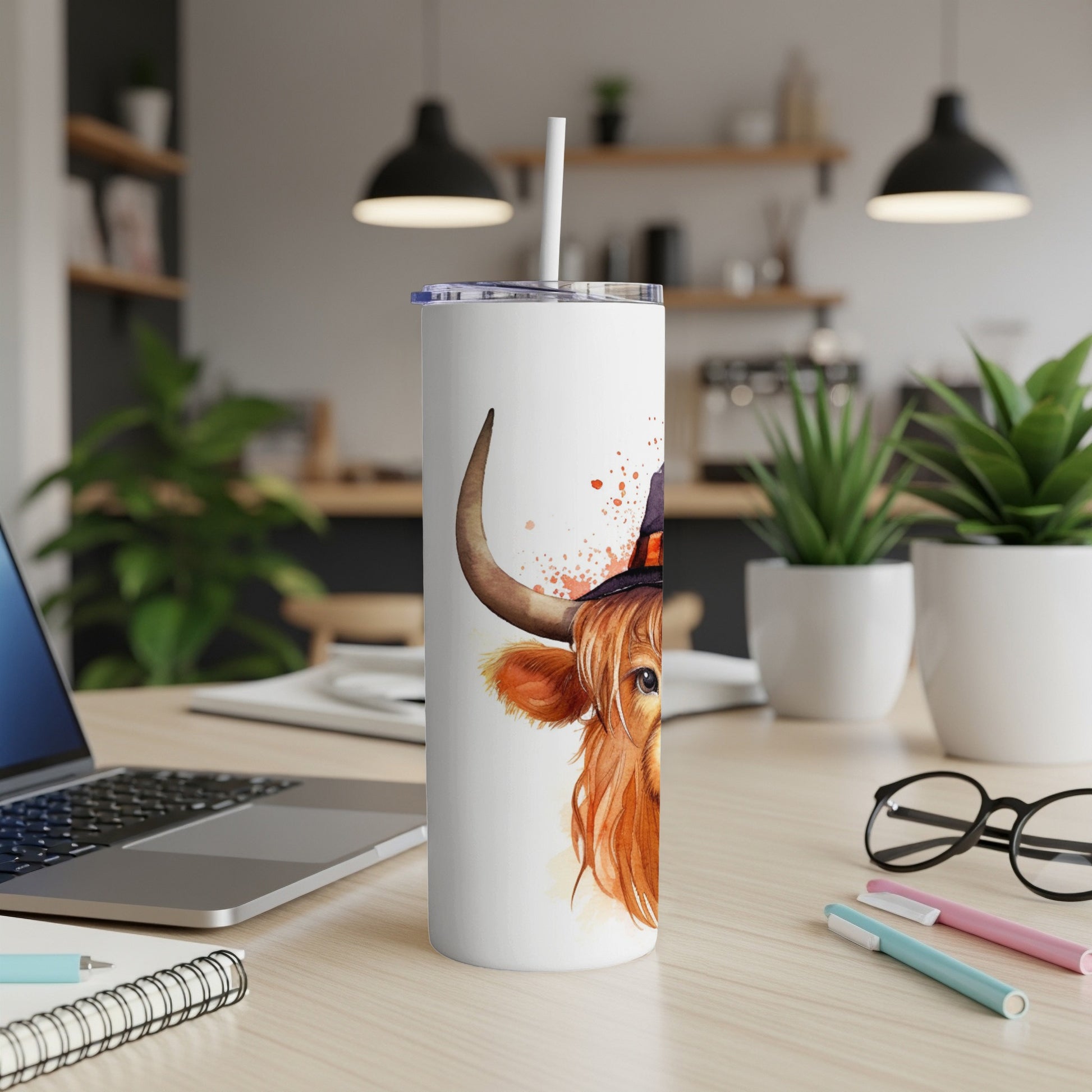 Highland cow with witch hat on a white tumbler with straw.