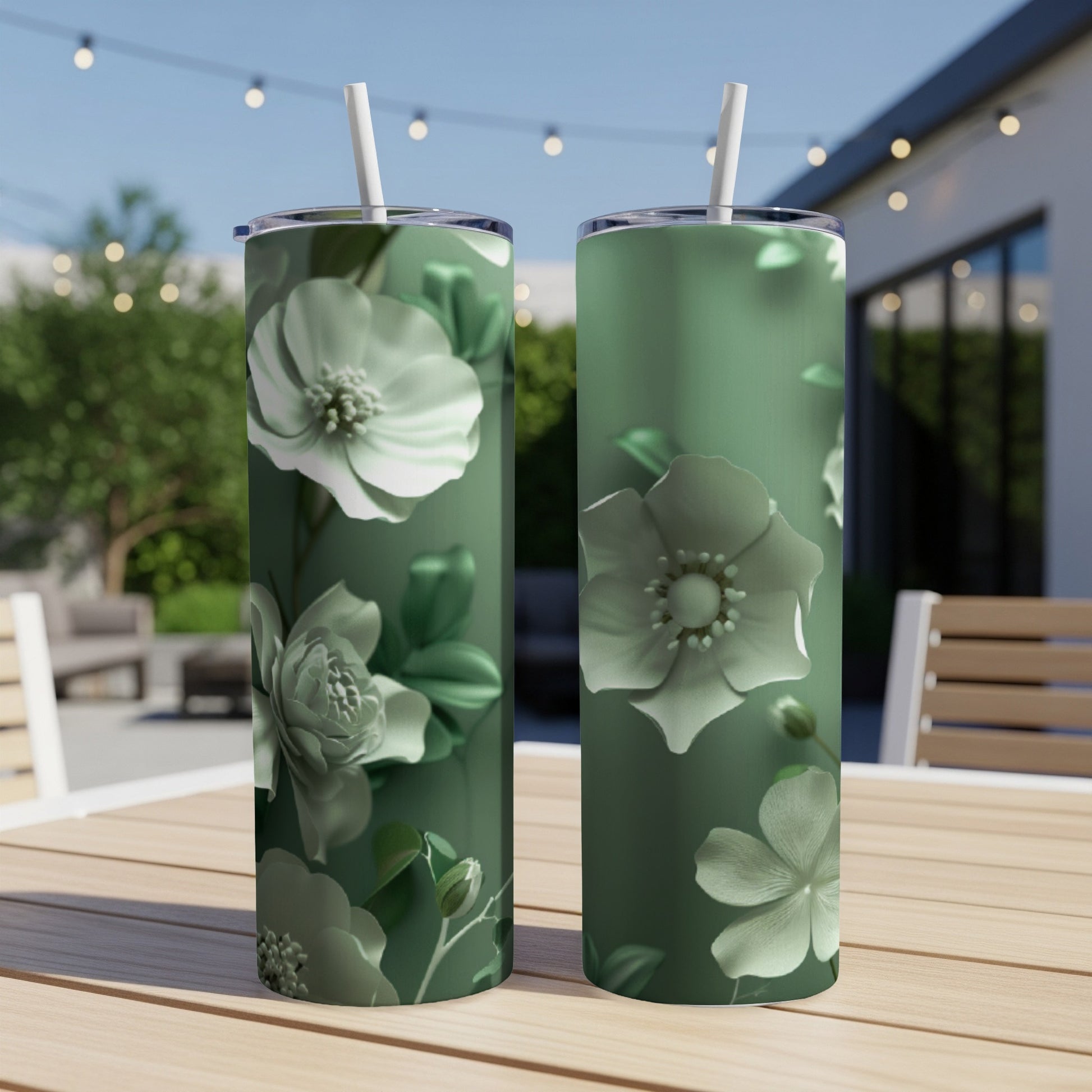 Two green tumblers with white floral designs sit on a wooden table.