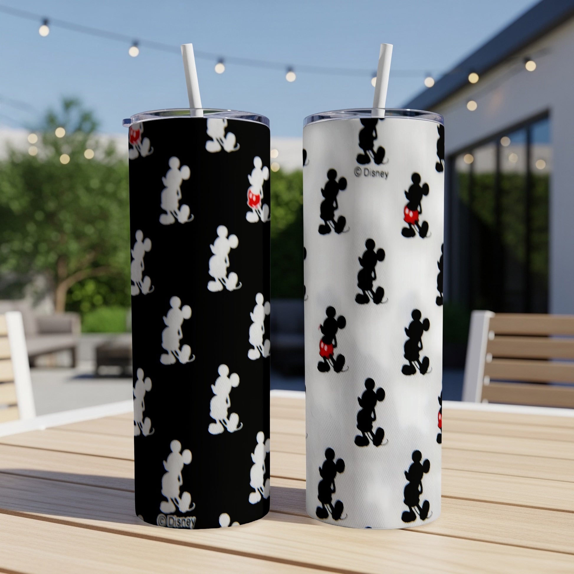 Two Disney Mickey Mouse tumblers, one black and one white, on a table.