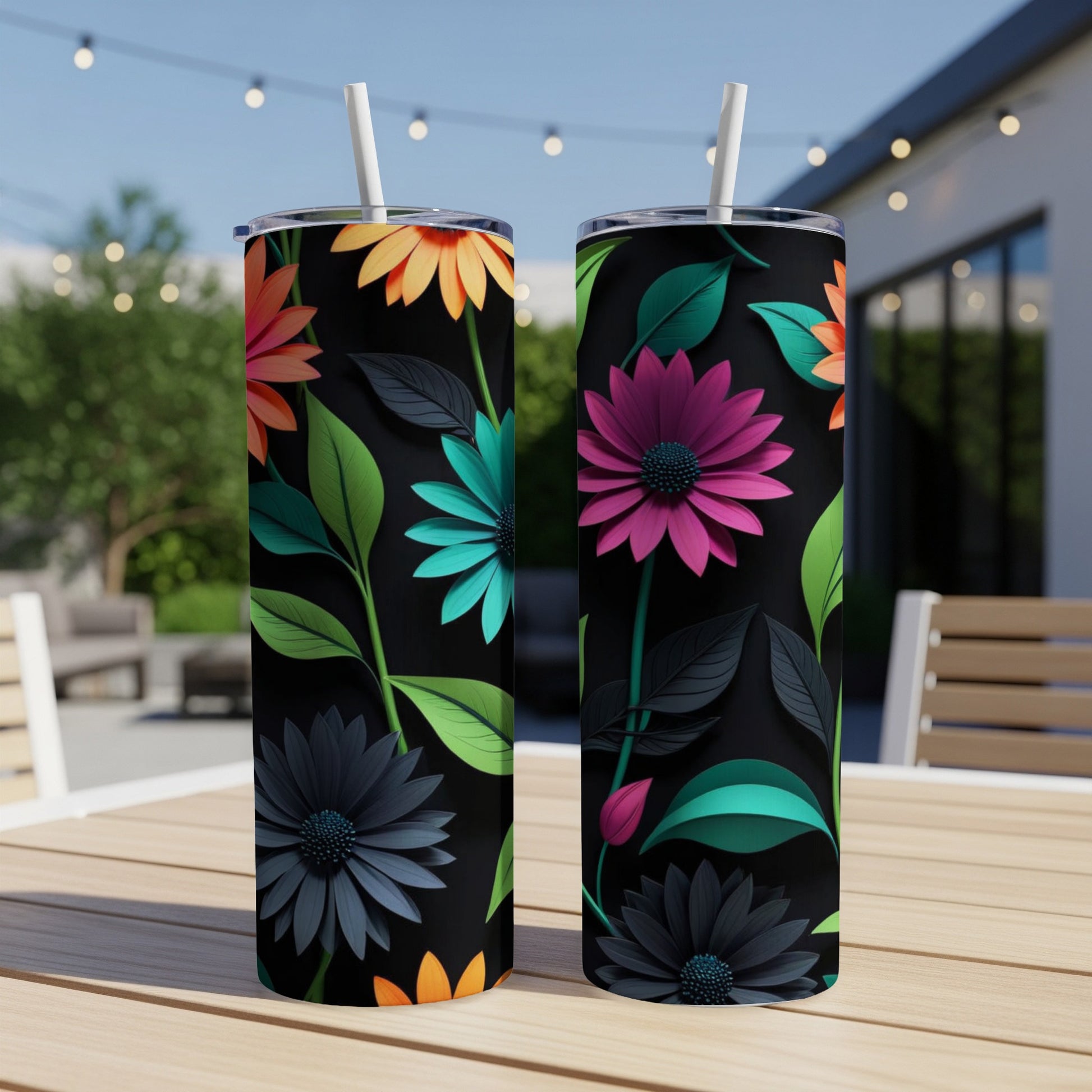Two black tumblers with vibrant floral patterns on an outdoor table.