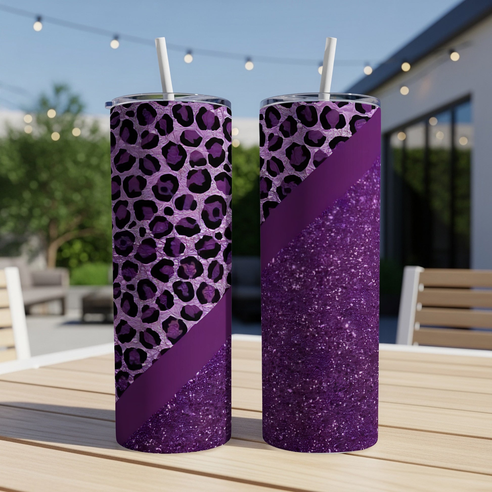 Two tall purple tumblers with leopard print and glitter designs on a table.