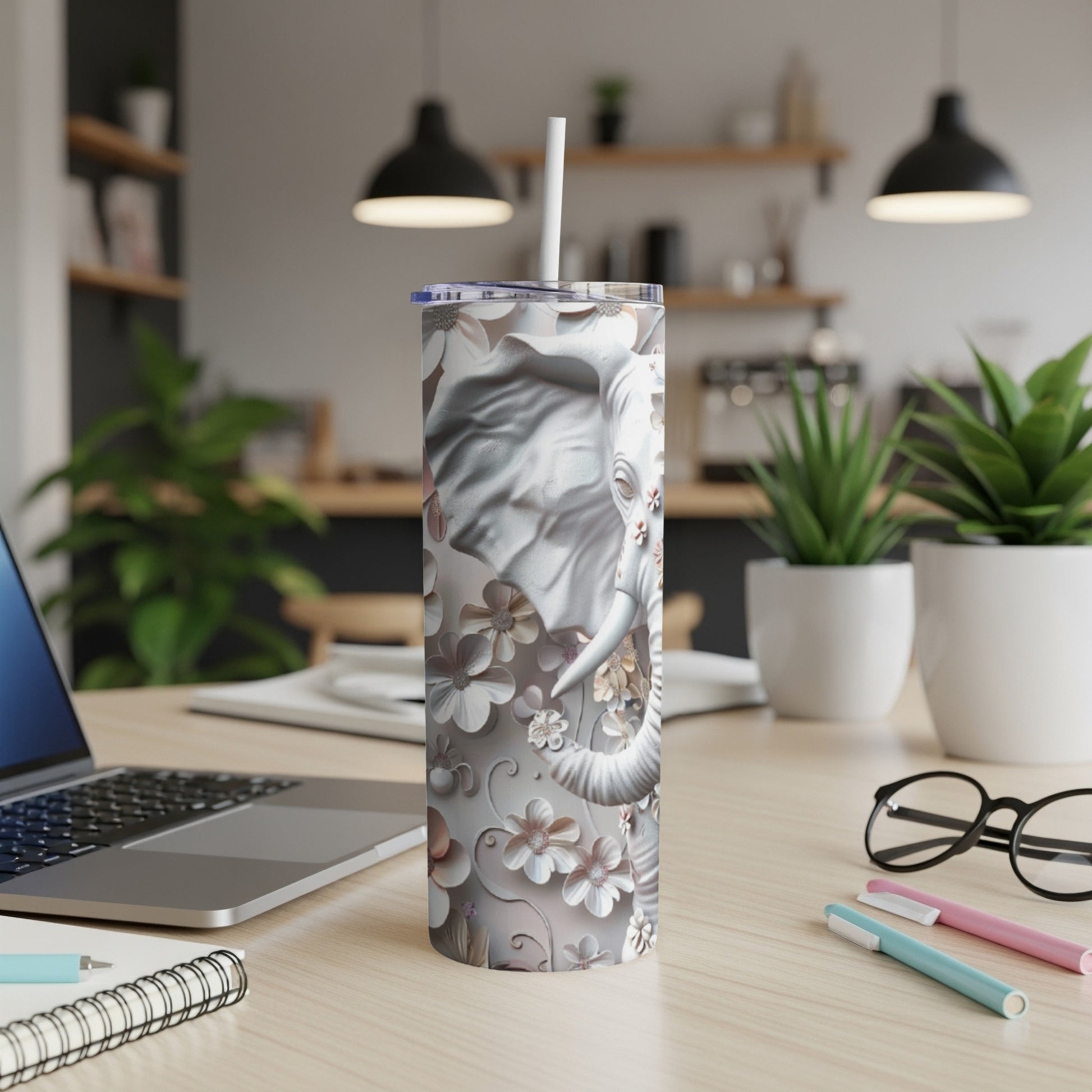 White tumbler with floral elephant design on a desk.