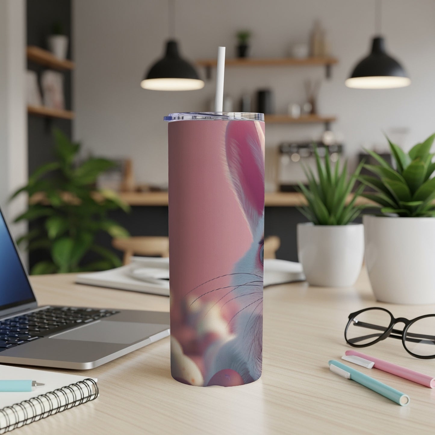 Pink tumbler with Easter bunny design on a desk with a laptop.