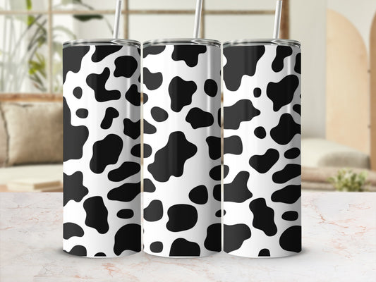 Three tumblers with a black and white cow print pattern, standing on a marble surface.
