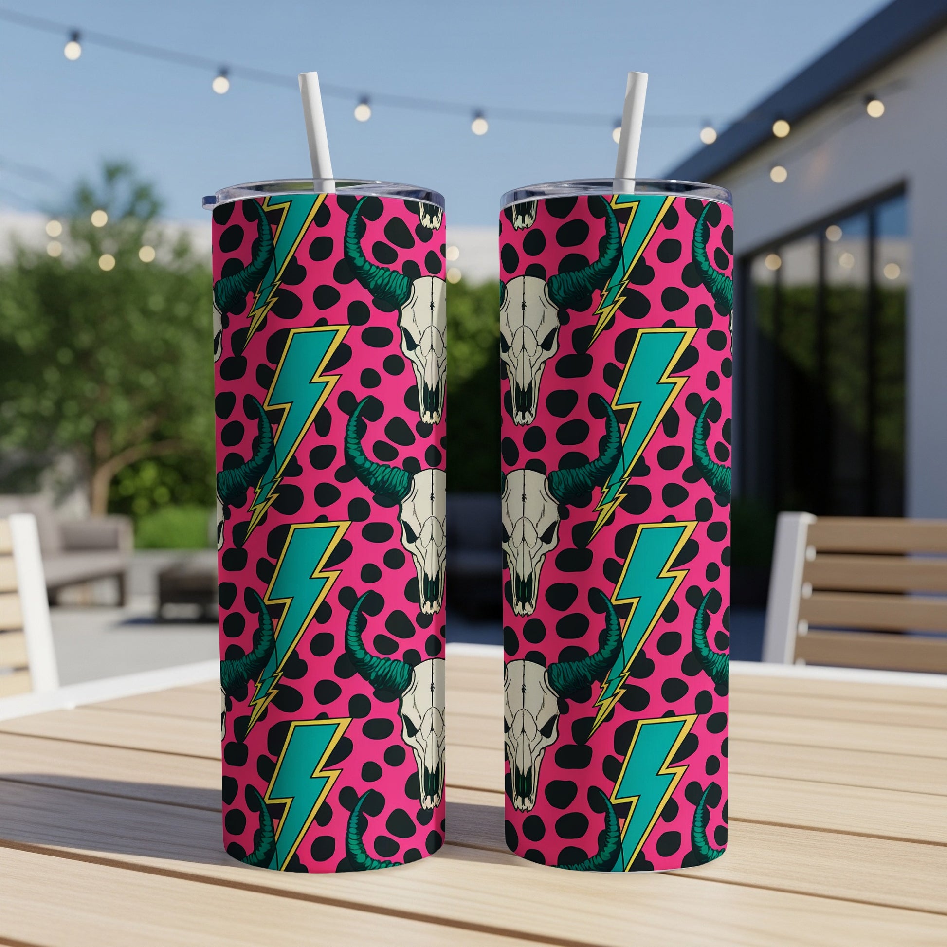 Two tumblers with pink background, black cow skulls, and teal lightning bolts.
