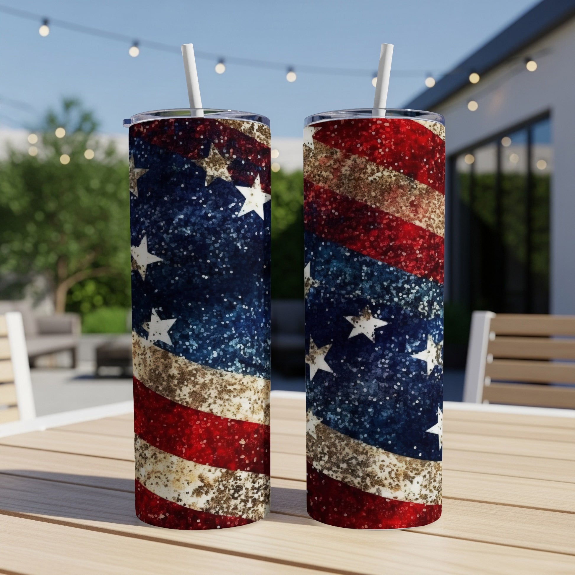 Two patriotic glitter tumblers with stars and stripes design on outdoor table.