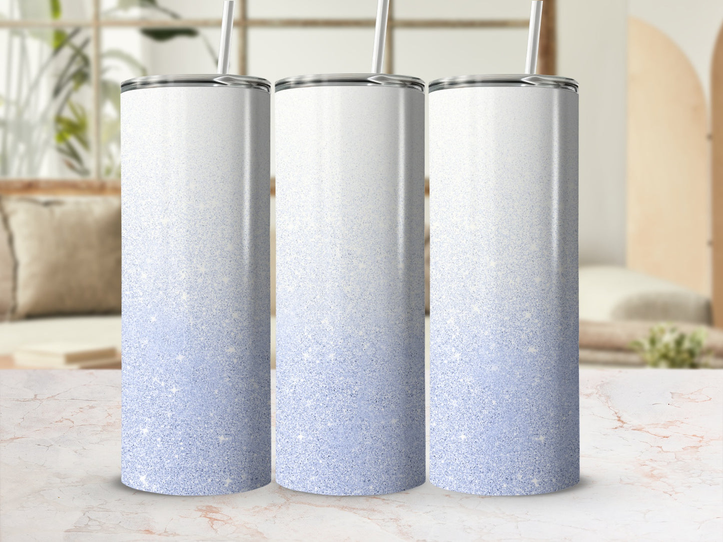Three glittery blue ombre tumblers with straws stand side by side.
