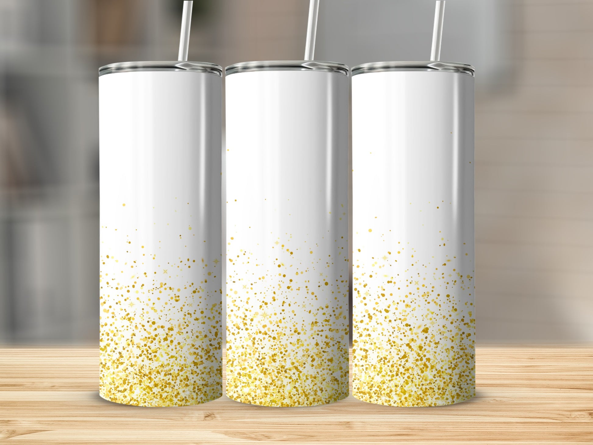 Three white tumblers with gold glitter splatter on a wooden surface.