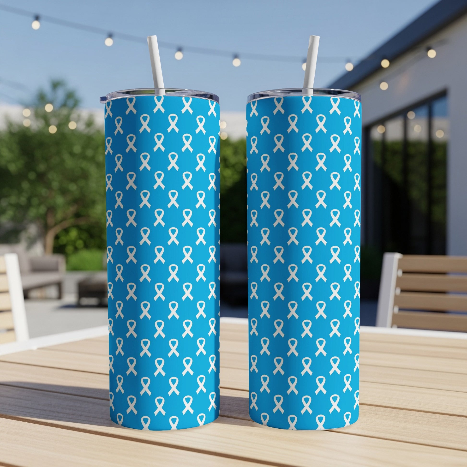 Two blue tumblers with a white ribbon pattern, shown outdoors on a table.