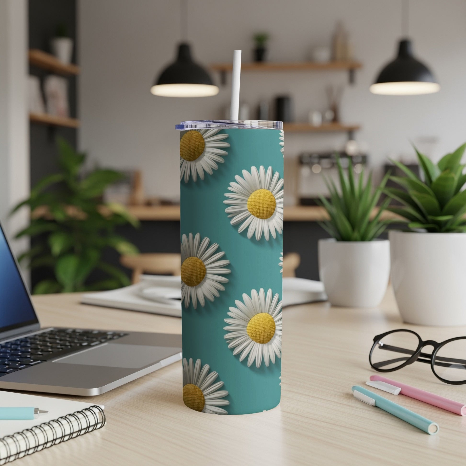 Teal tumbler with repeating daisy pattern and white straw on a desk.