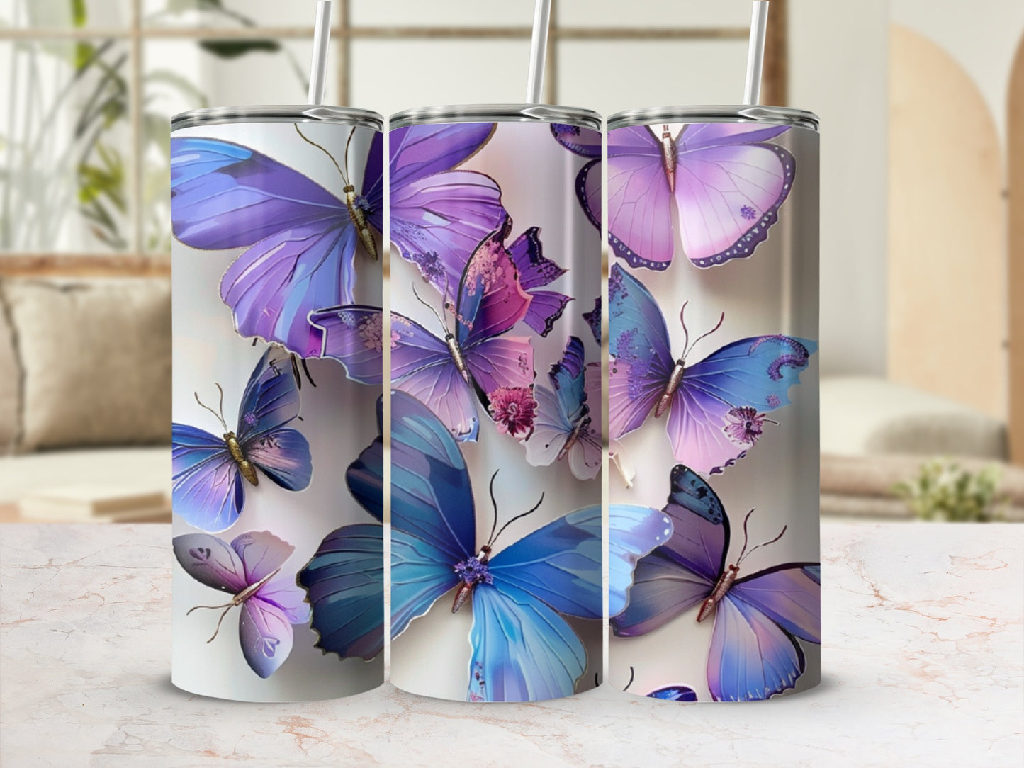 Three tumblers with purple and blue butterfly designs and white straws.