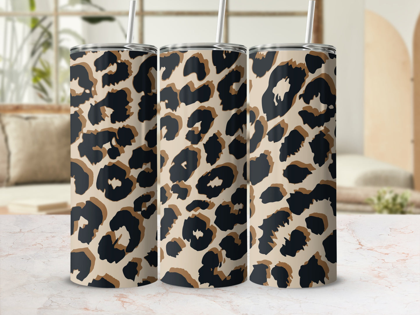 Three tumblers with leopard print design displayed on a marble surface.