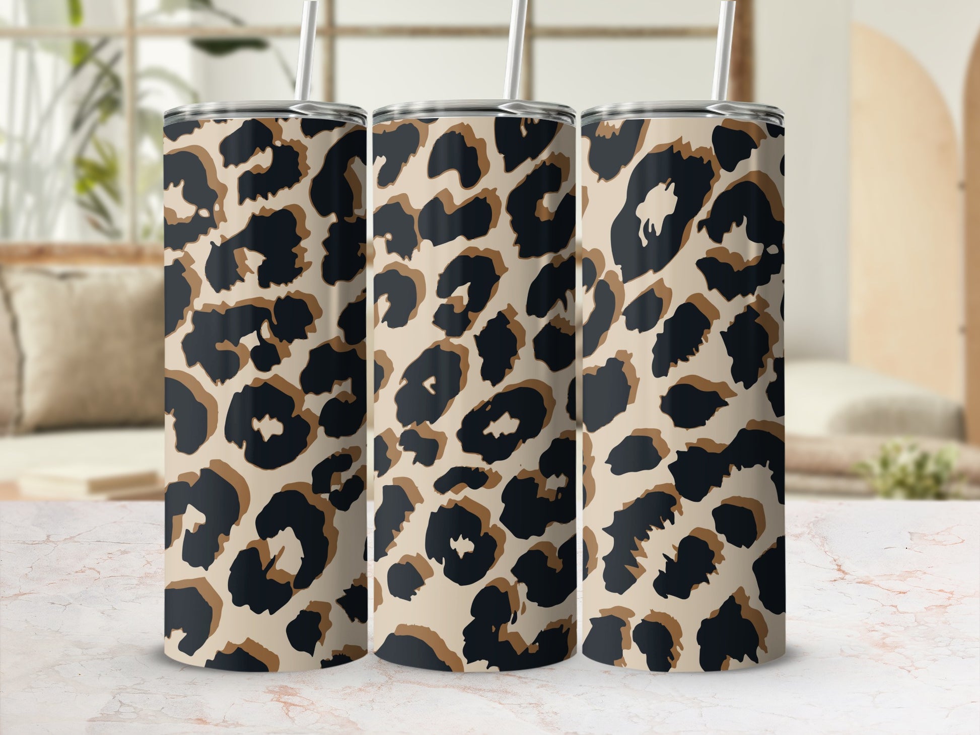 Three tumblers with leopard print design displayed on a marble surface.