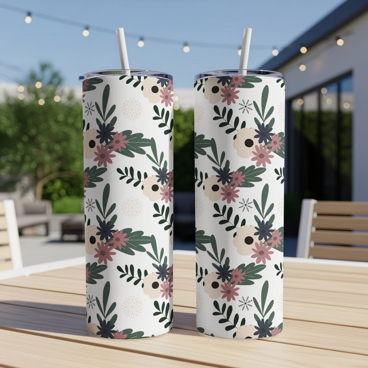 Two white tumblers with a floral pattern sit on a wooden table outdoors.