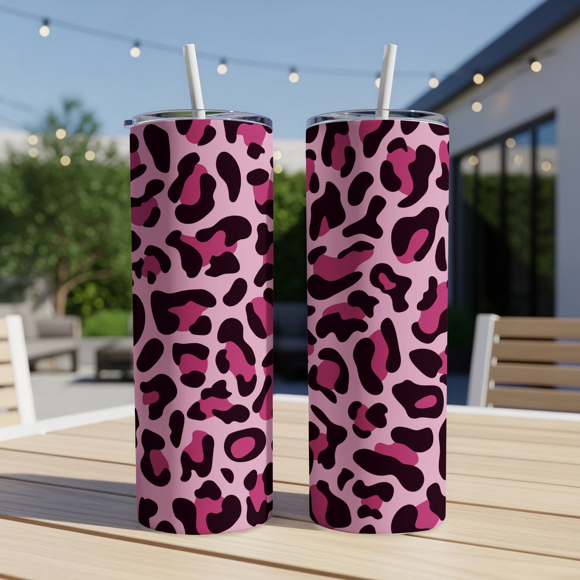 Two pink tumblers with a dark pink and black leopard print pattern and straws.