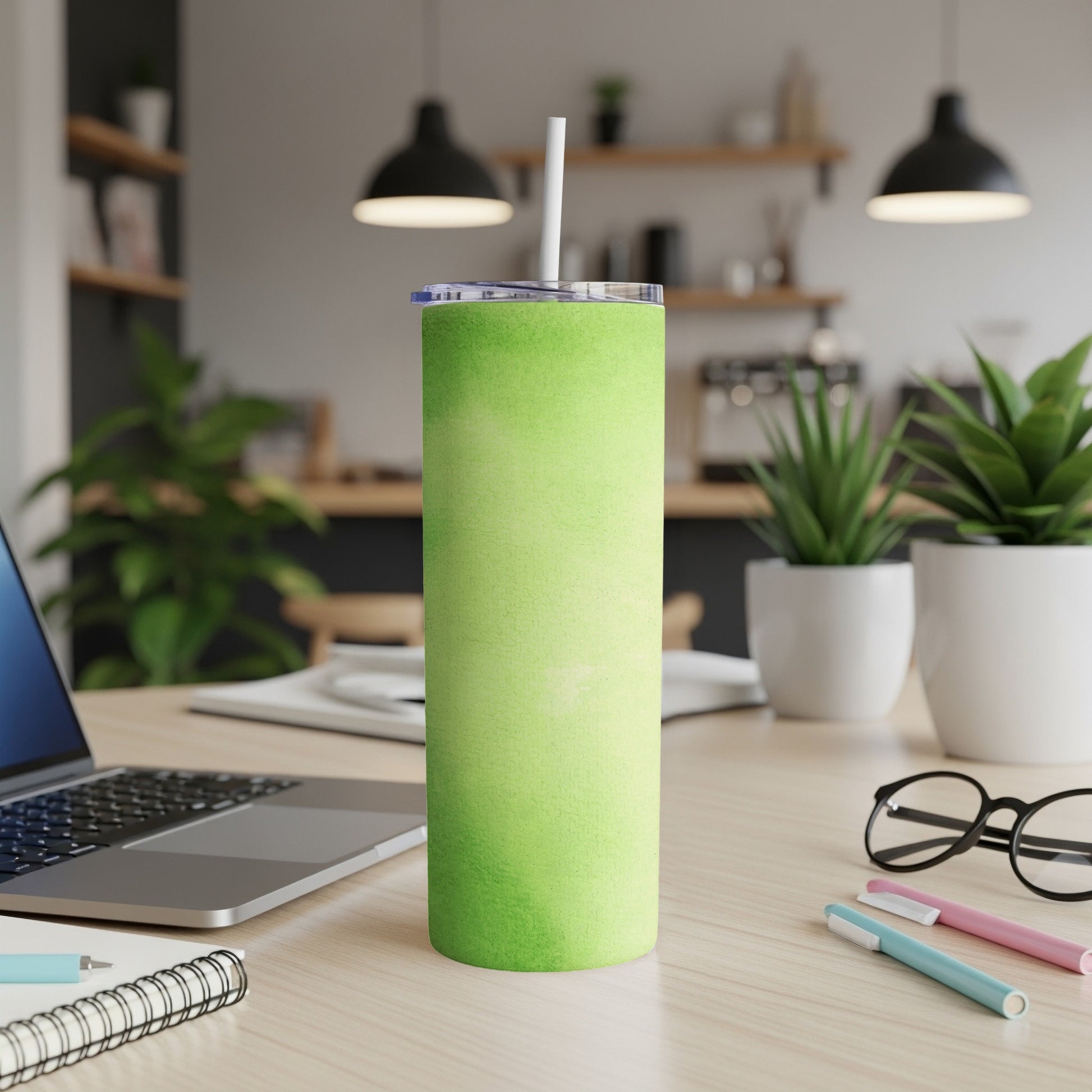 Green speckled tumbler with straw on a wooden desk.